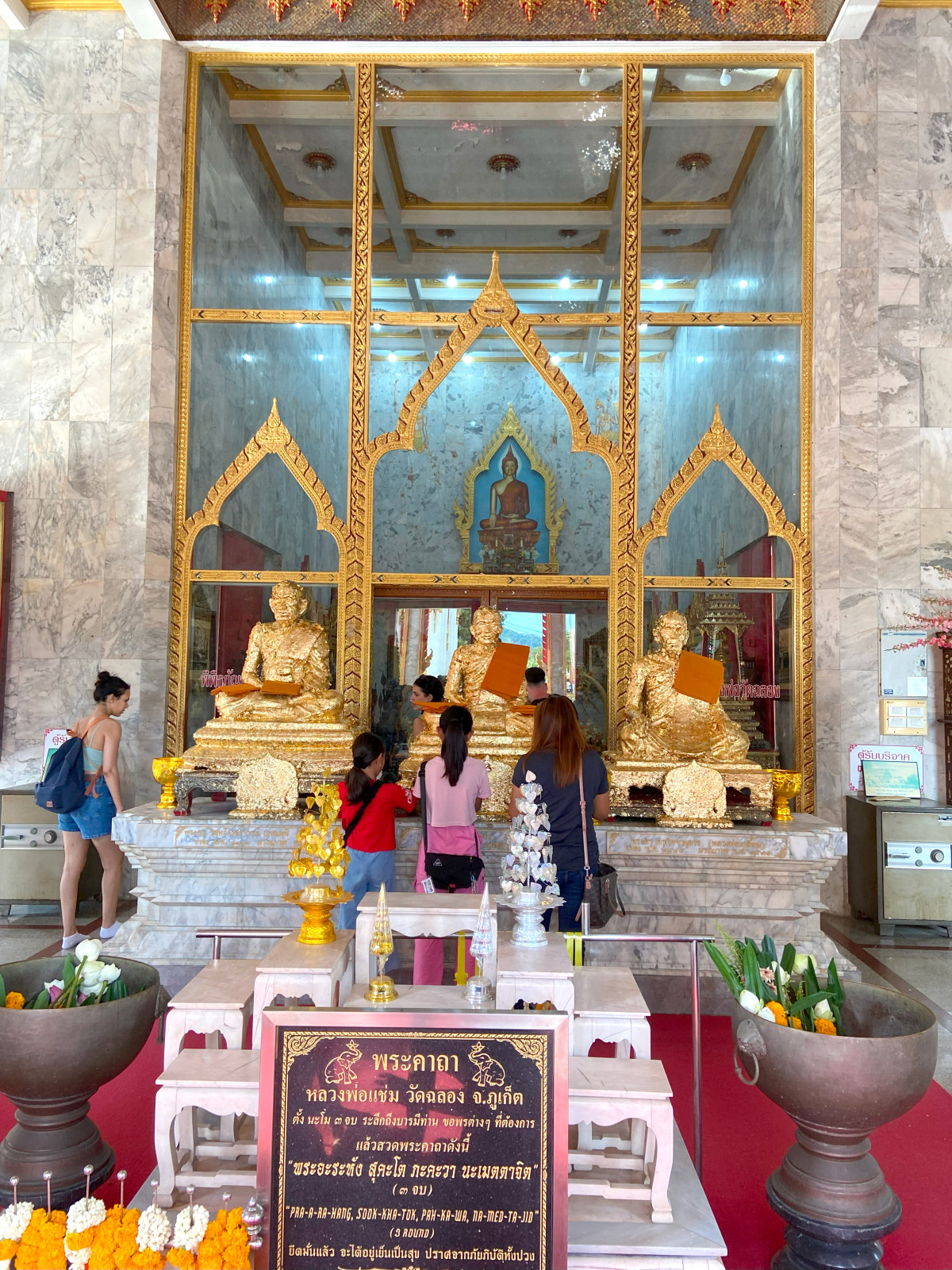 Inside a Thai temple, devotees pay their respects and place gold leaf on the beautiful, gilded Buddha statues