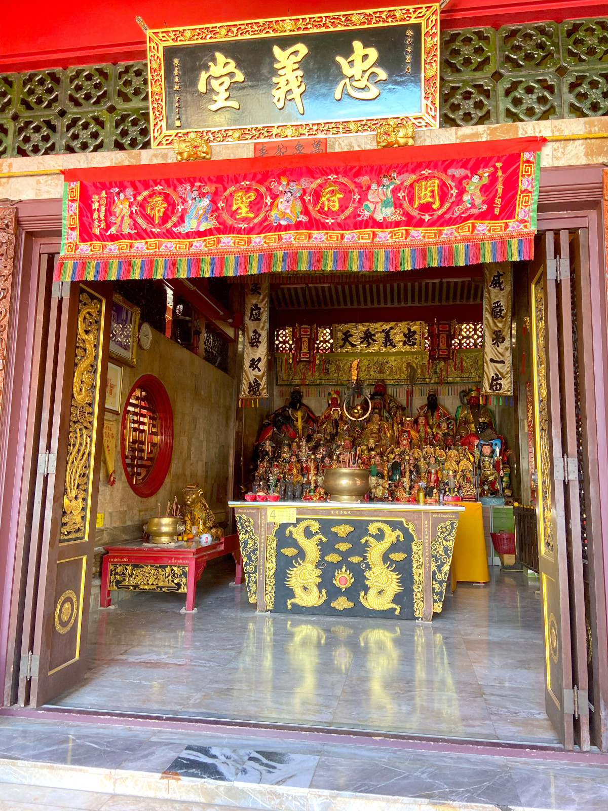 The vibrant and detailed altar inside a Chinese temple or shrine, featuring multiple deities and intricate gold and red decorations